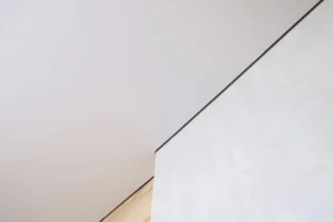 Detail prechodu napínaného stropu na stenu s precíznym ukončením a čistou líniou bez viditeľných spojov.