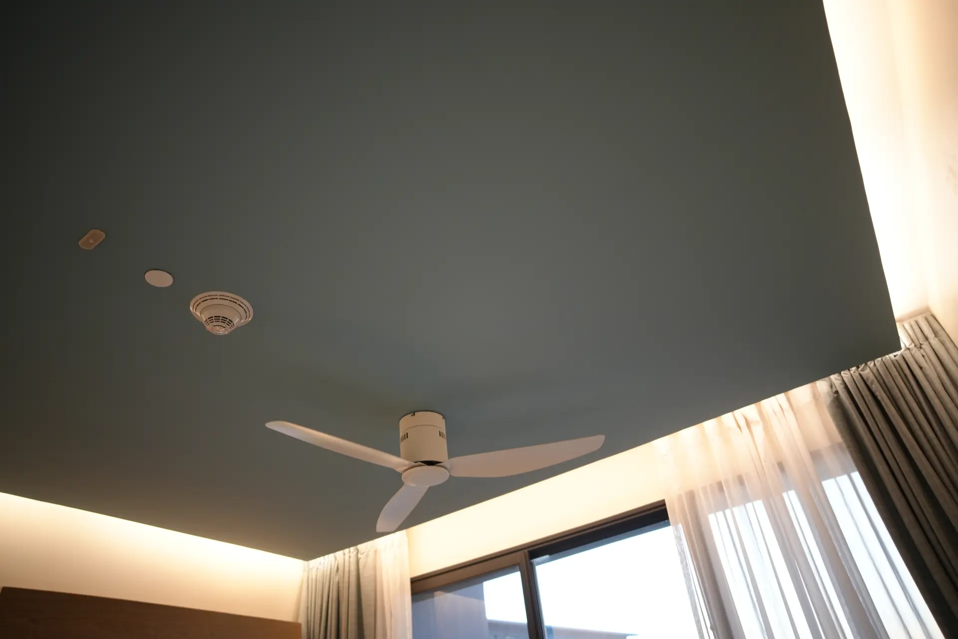 Moderný farebný napínaný strop so stropným ventilátorom a obvodovým LED osvetlením v štýlovej obývacej izbe.