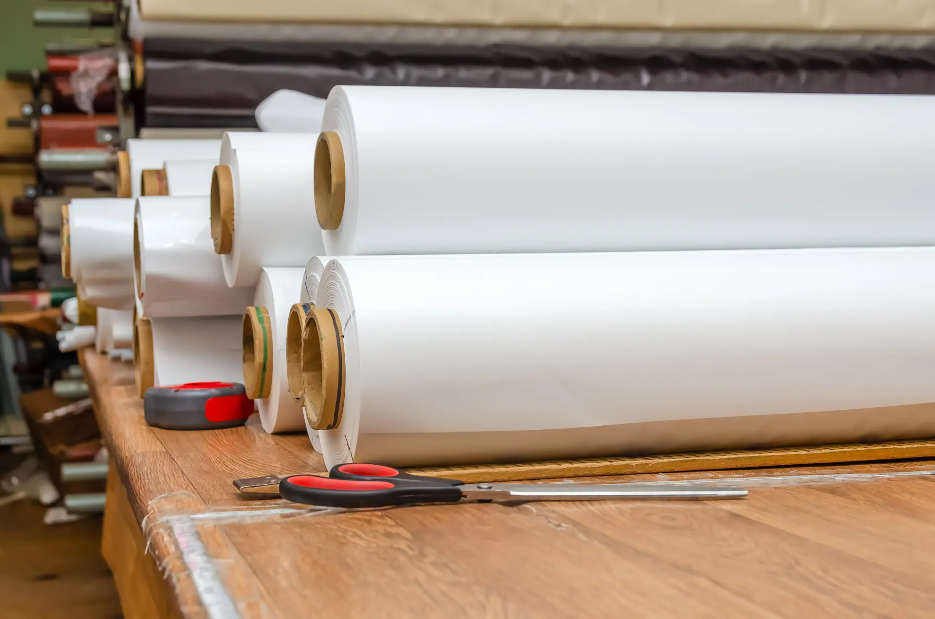 Rolky PVC fólie na napínané stropy uložené v dielni, pripravené na rezanie a výrobu stropov na mieru.