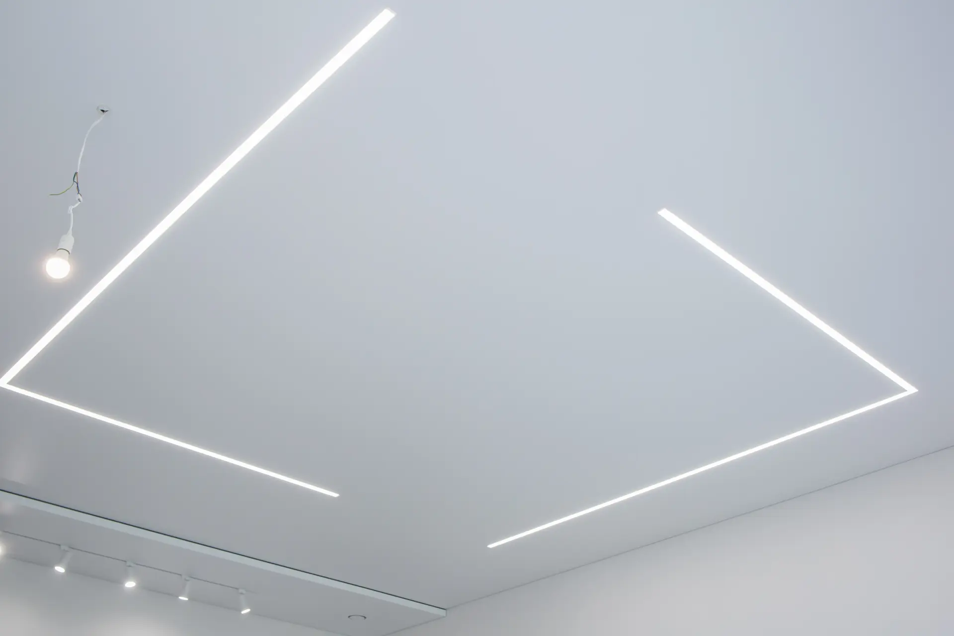 Napínaný strop s minimalistickými líniovými LED svetlami zabudovanými do stropnej plochy, ktoré dodávajú priestoru moderný a futuristický vzhľad.