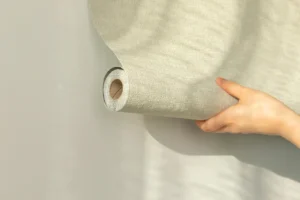 Prikladanie tapety na stenu počas interiérových úprav s dôrazom na presné zarovnanie.