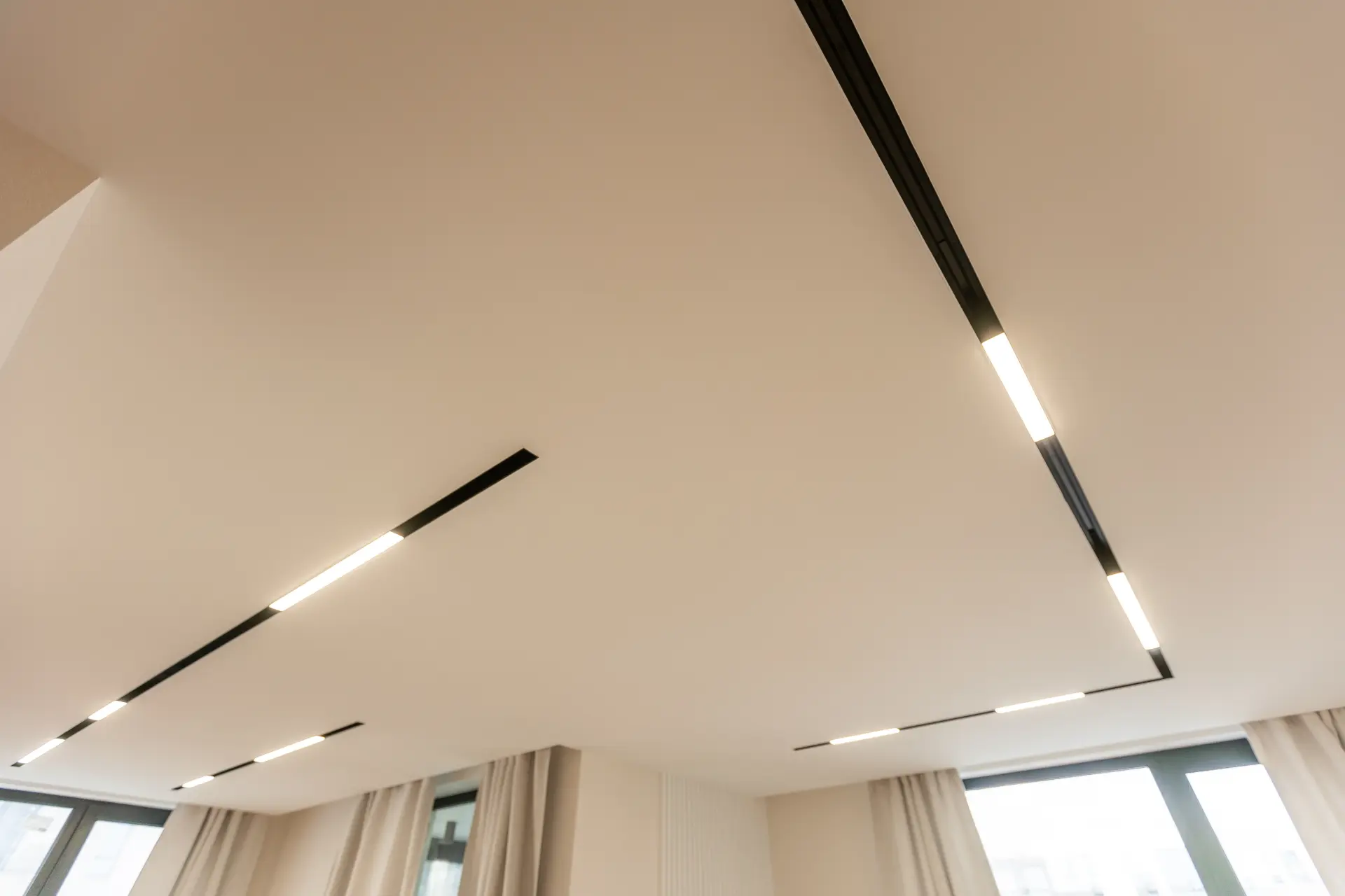 Napínaný strop s modernými líniovými LED svietidlami zapustenými do stropnej plochy v elegantnom interiérovom dizajne.