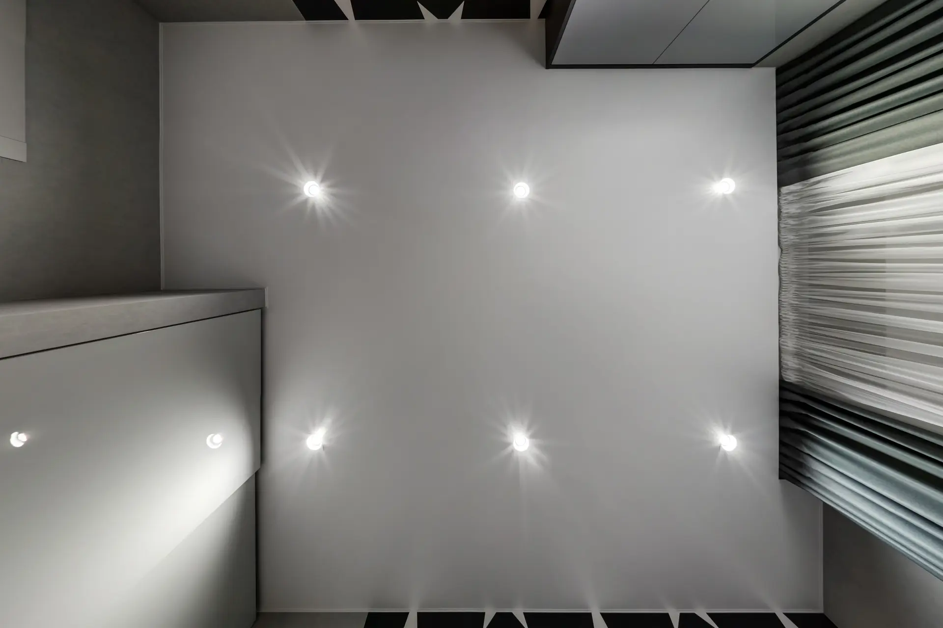 Biely napínací strop s integrovanými LED bodovými svetlami v modernom interiéri.