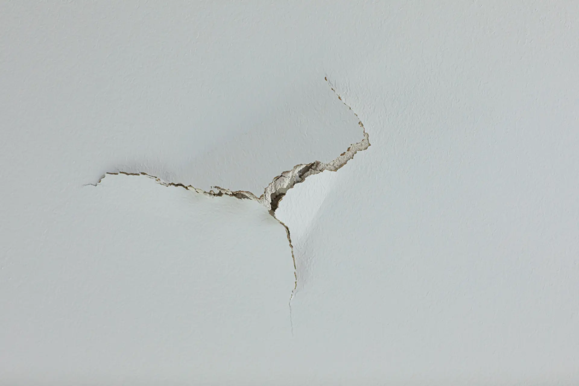Detail praskliny v omietke na stene naznačujúcej poškodenie alebo sadanie stavby.