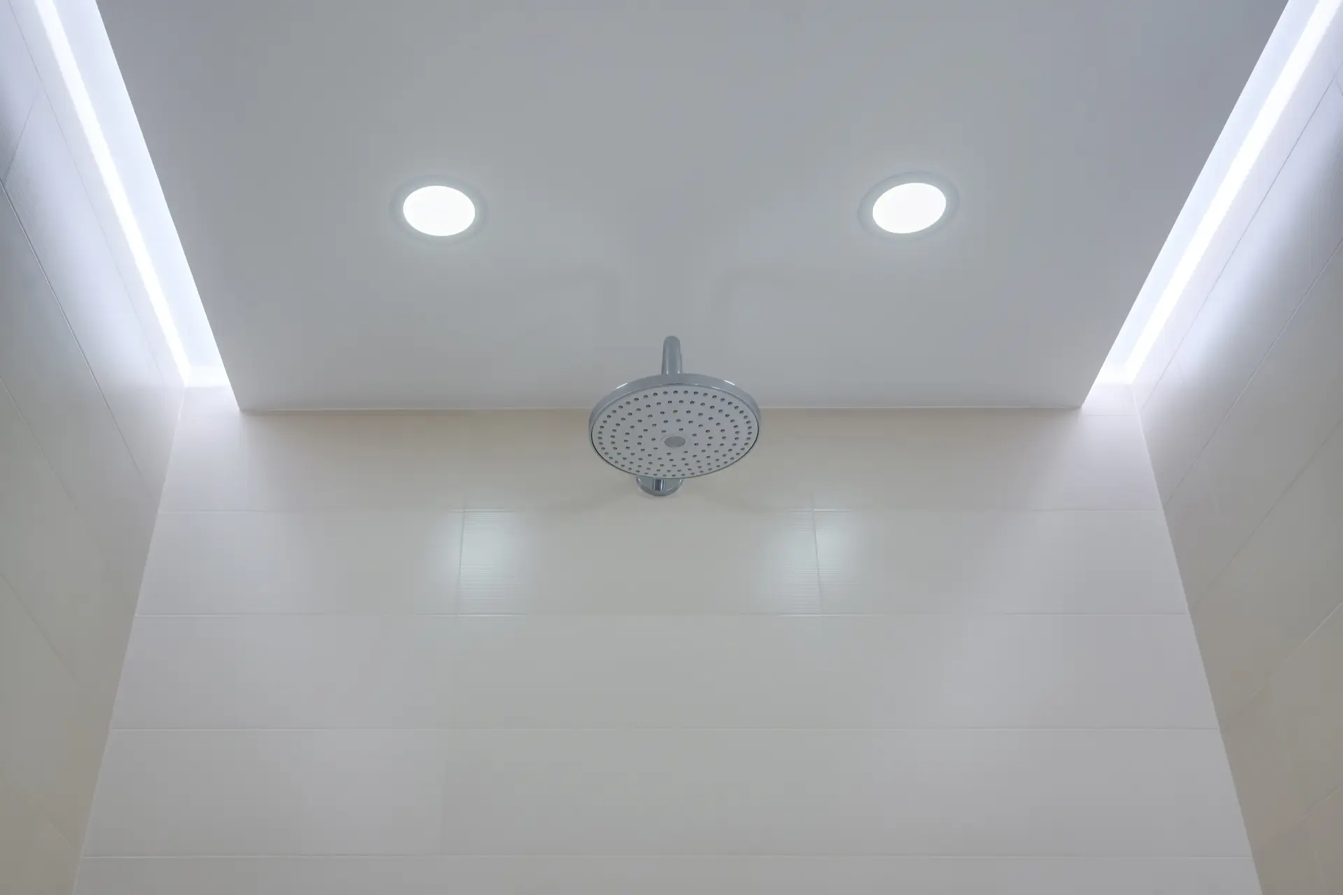 Moderný sprchový kút s bielym napínacím stropom, zapustenými LED svetlami a nepriamym osvetlením po obvode.
